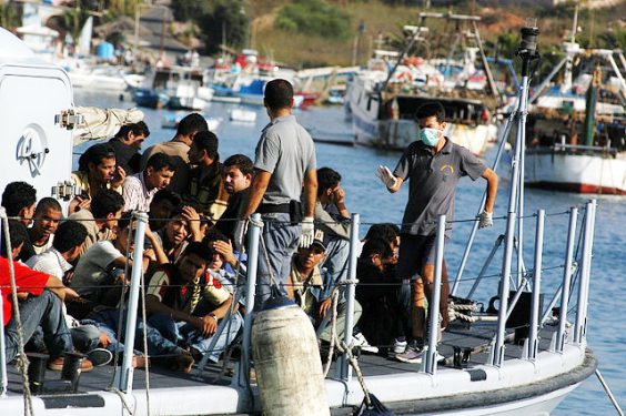 Migrants arriving at the island of Lampedusa by boat. Image via Wikipedia.